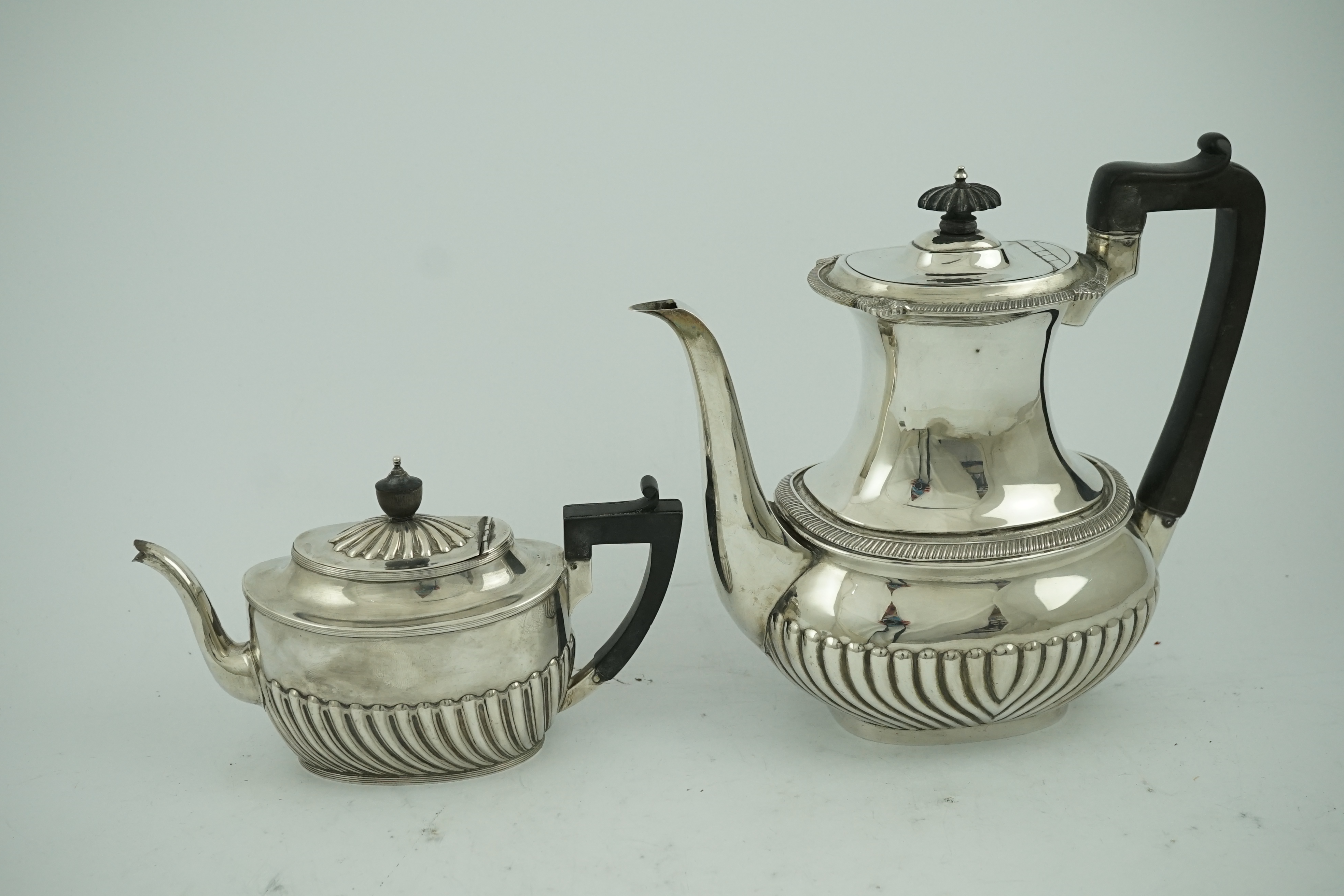 An Edwardian demi-fluted silver oval coffee pot by Mappin & Webb, Sheffield, 1902 and a similar tea pot by Henry Harrison, Sheffield, 1884